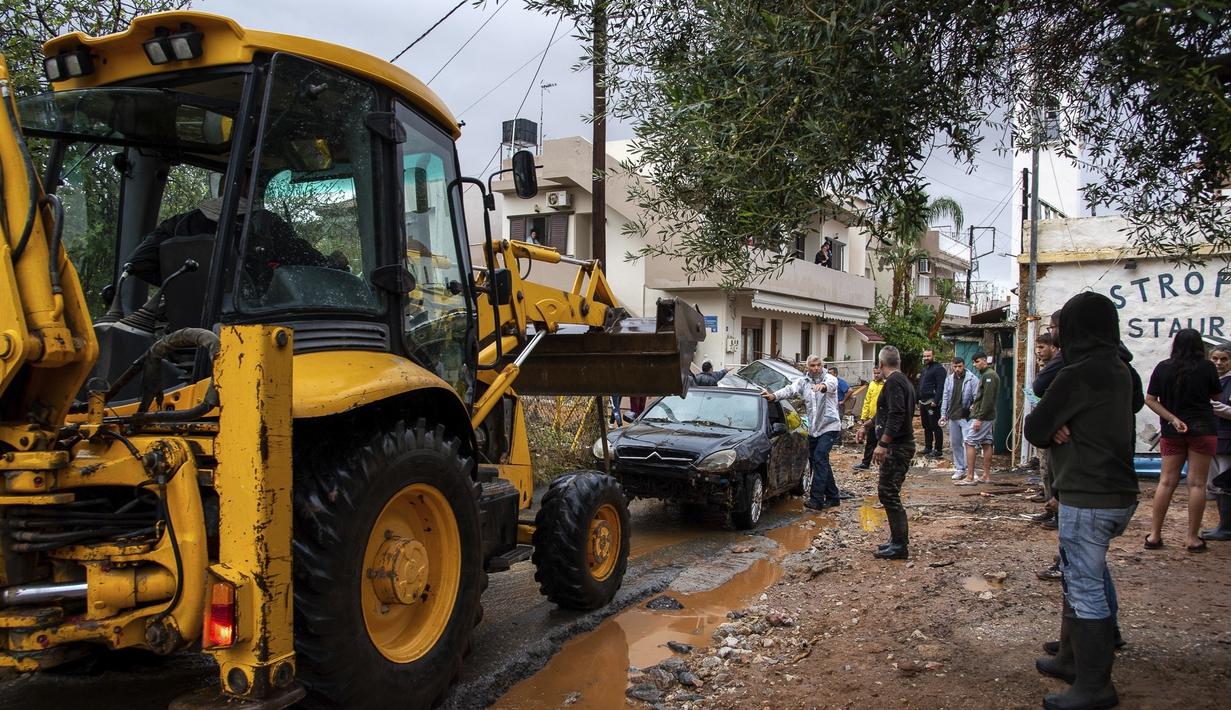 Warga mencoba membersihkan jalan dari puing-puing setelah hujan lebat di desa Malia, pulau Kreta, Yunani, Selasa (10/11/2020). Banjir besar di Pulau Kreta Yunani merusak jalan, membanjiri ratusan rumah, dan menyeret mobil ke laut di tengah hujan deras yang sedang berlangsung. (AP Photo/Harry Nakos)