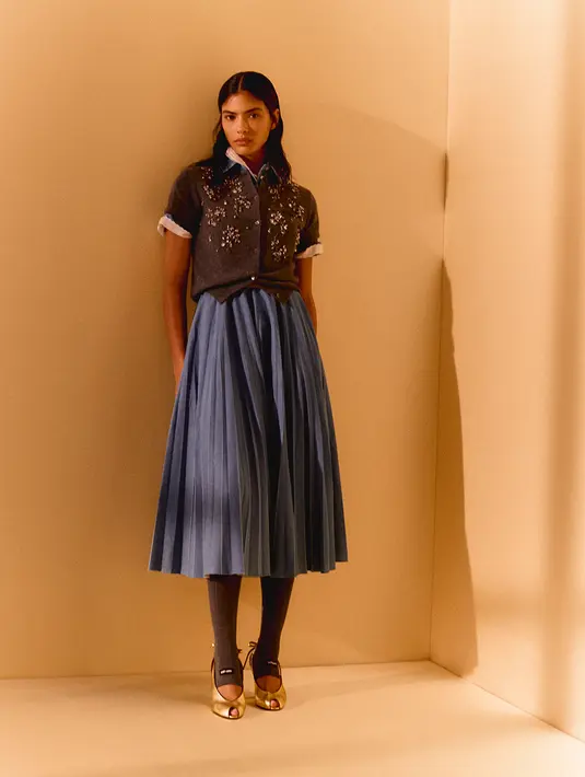 Gaya busananya meliputi rok lipit panjang, rajutan berkancing, summer shirt, dan jaket beritsleting [Miu Miu]