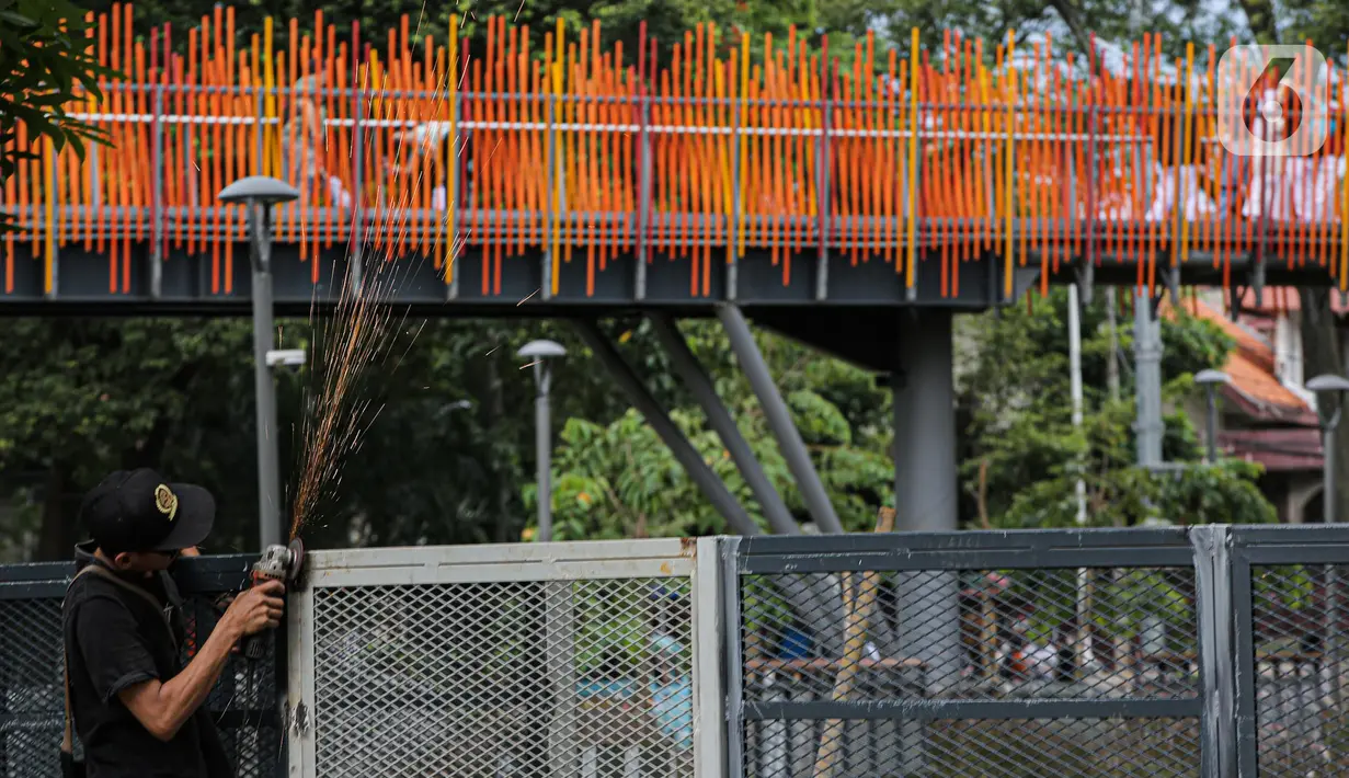 Pekerja melakukan pengelasan saat menyelesaikan pemasangan pagar yang mengelilingi area ruang terbuka hijau (RTH) Tebet Eco Park, Jakarta, Senin (12/12/2022). Pemasangan pagar tersebut membuat taman terkesan lebih rapih dan bagus. (Liputan6.com/Faizal Fanani)