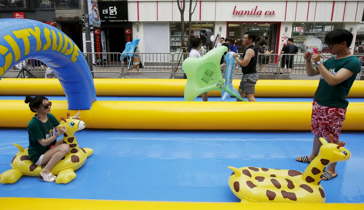 Beberapa peserta berfoto dalam acara yang bertajuk City Slide Festa 2015 di pusat kota Seoul, Korea Selatan, Minggu (19/07/2015). Seluncuran air dengan panjang 350 meter ini merupakan yang terpanjang di Korea. (REUTERS/Kim Hong-Ji)
