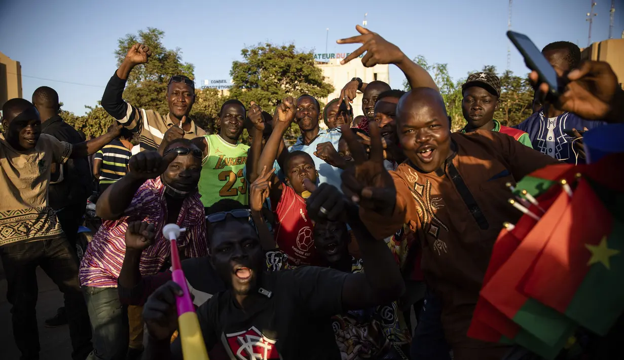 Kerumunan merayakan pengumuman bahwa Letnan Kolonel Paul Henri Sandaogo Damiba mengambil kendali negara di Ouagadougou, Burkina Faso, Senin (24/1/2022). Kudeta berlangsung sehari setelah penembakan di sejumlah barak militer di Ibu Kota Ougadougou dan dekat kediaman Presiden Kabore (AP/Sophie Garcia)