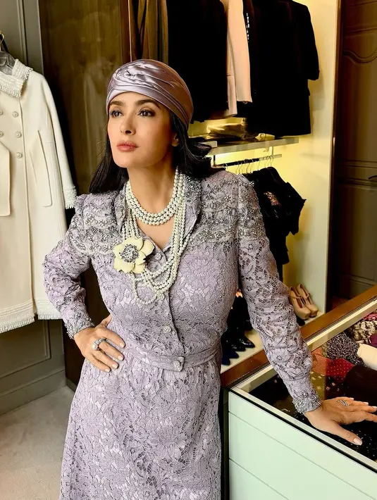 Salma Hayek tampak anggun dalam gaun renda ungu dan ikat kepala sutra, sementara model Italia dan Prancis Carla mengenakan mantel berhias putih dan emas. [Dok/Valentino].