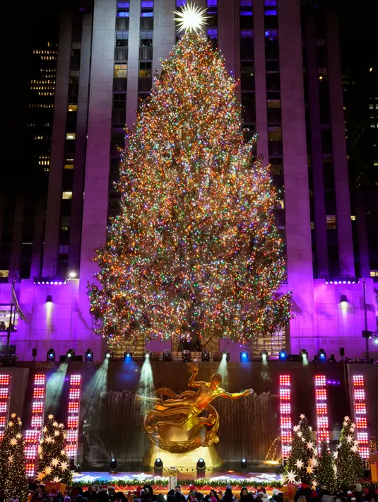 <p>Wali Kota New York Eric Adams membantu menekan tombol yang menerangi pohon itu sementara Paduan Suara Kaum Muda dari Kota New York menyanyikan "Joy to the World." (Photo by Charles Sykes/Invision/AP)</p>