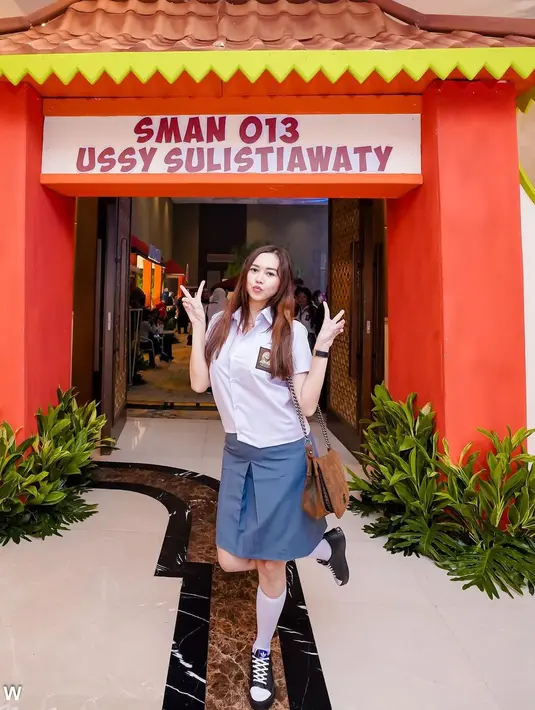 Tampil mengenakan atasan putih, rok abu-abu dan membawa tas, Aura Kasih terlihat berpose saat tiba di lokasi acara perayaan ulang tahun ke-41 Ussy Sulistiawaty. Aura Kasih tidak lupa berfoto. Ia terlihat mengacungkan dua jari sambil mengangkat kaki kanan ke belakang. (Instagram/aurakasih)