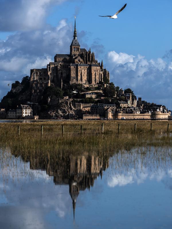 Kastil Mont Saint-Michel terlihat di Normandia, Prancis barat laut (1/9/2019). Dahulu Mont Saint Michel awalnya terhubung dengan daratan utama melalui sebuah jembatan kecil. Namun pada saat pasang jembatan tersebut tertutup dan terlihat pada saat surut. (AFP Photo/Joel Saget)