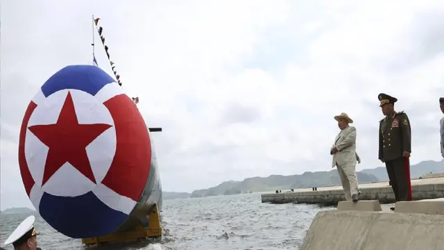 Pemimpin Korea Utara Kim Jong Un (kedua dari kanan) di samping kapal selam serang nuklir taktis. (STR / KCNA VIA KNS/AFP)