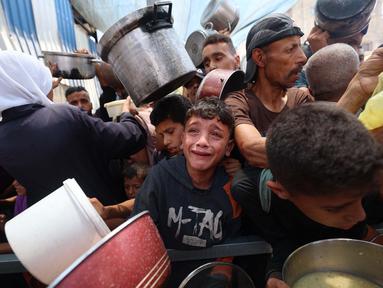 Salah satu anak Palestina menangis saat menunggu pembagian makanan di sebuah titik distribusi di Nuseirat, Jalur Gaza Tengah, pada 11 Juni 2025. (Eyad BABA/AFP)