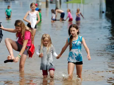 Anak-anak bermain di jalan banjir setelah hujan lebat di Minsk, Belarus, Rabu (13/7). (REUTERS / Vasily Fedosenko)