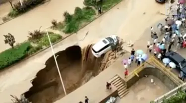 Sebuah mobil terseret arus banjir bandang hingga nyaris masuk ke dalam sinkhole di China. Warga bekerja sama menyelamatkan mobil tersebut.