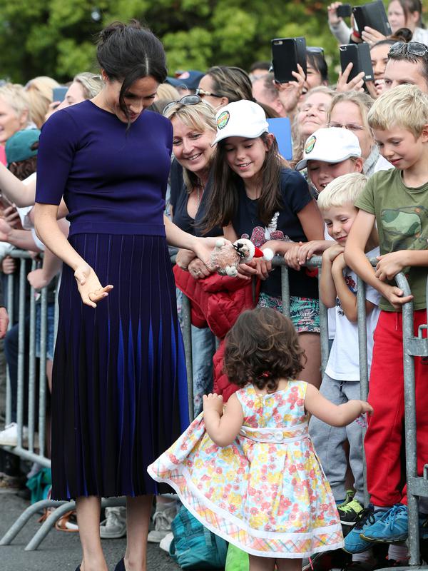Duchess of Sussex, Meghan Markle menyapa anak kecil saat berjalan di Taman Pemerintah Rotorua, Selandia Baru, Rabu (31/10). Meghan dan Pangeran Harry sedang dalam tur tiga minggu di Australia, Selandia Baru, Tonga, dan Fiji. (Michael Bradley/Pool/AFP)