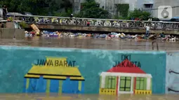 Tumpukan sampah tersangkut di sebuah jembatan di Jalan Jatinegara Barat, Jakarta, Kamis (2/1/2020). Hujan yang terjadi kemarin malam membuat Kali Ciliwung meluap ke jalan. (merdeka.com/Imam Buhori)