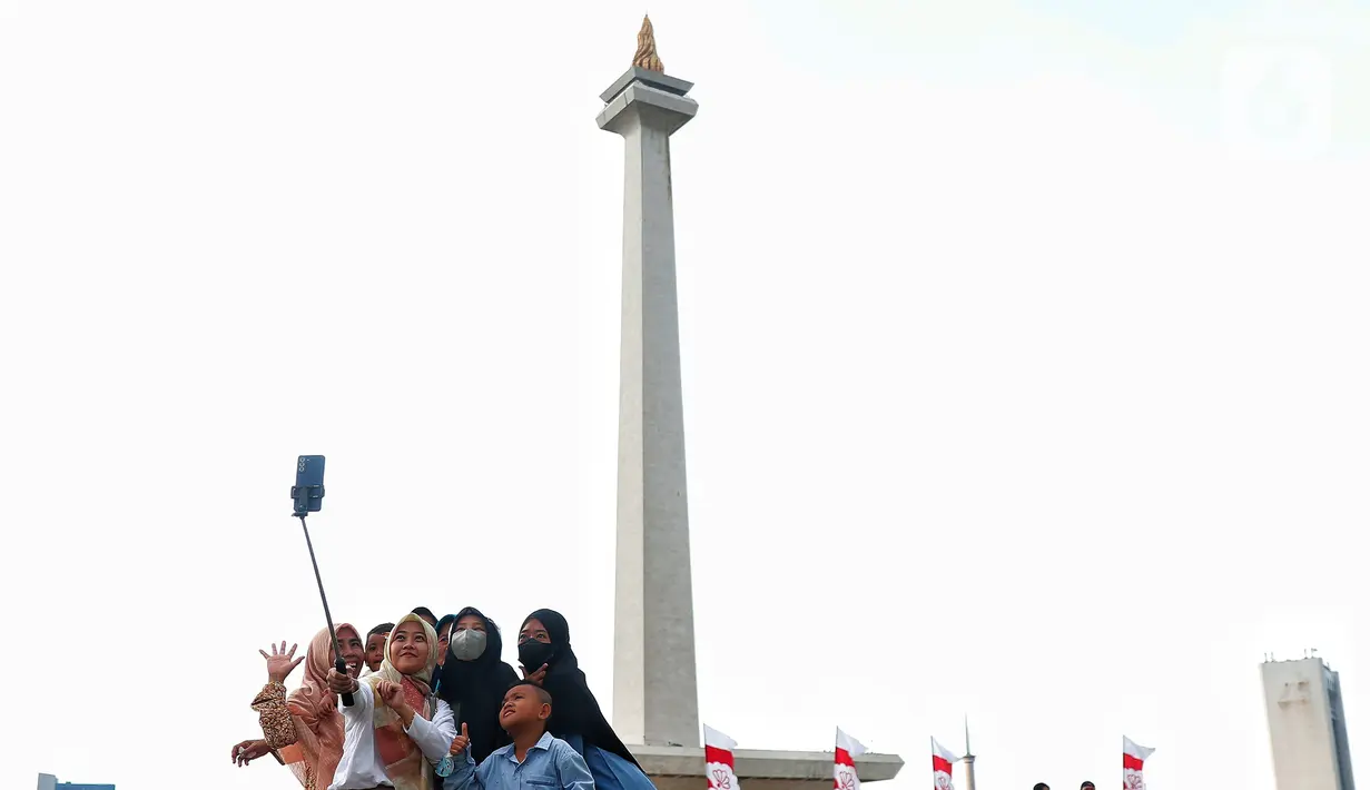 Pengunjung saat berswafoto dengan latar Tugu Monas, Jakarta. (Liputan6.com/Angga Yuniar)