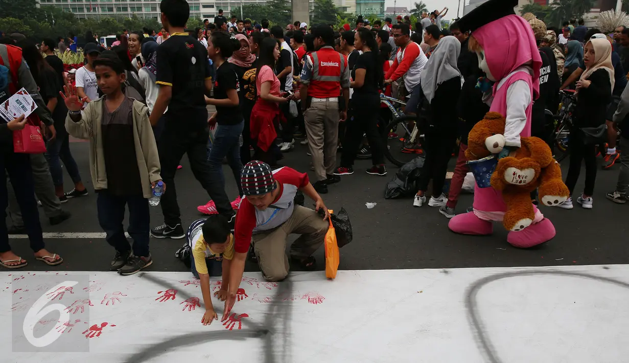 Pengunjung bersama anaknya ikut berpartisapasi dalam erakan Deklarasi Anti Korupsi di Bundaran HI, Jakarta, Minggu (27/11). Aksi ini dilakukan jelang diperinngatinya Hari Anti Korupsi Sedunia  9 Desember. (Liputan6.com/Johan Tallo) 