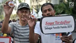 Warga menunjukan pin anti golput usai melakukan pendaftaran daftar pemilih tetap (DPT) di kawasan Car Free Day, Jakarta, Minggu (21/10). Pos pendaftaran ini bertujuan mendata warga yang belum terdaftar dalam DPT Pemilu 2019. (Merdeka.com/Iqbal S. Nugroho)