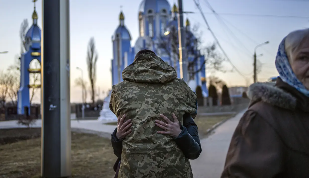 Seorang tentara memeluk kerabat yang melarikan diri dari perang, beberapa menit sebelum berangkat dengan bus menuju Polandia, di Vinnytsia, Ukraina, Rabu, 16 Maret 2022. (AP Photo/Rodrigo Abd)