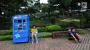 Warga berolahraga dekat anak yang sedang membaca buku di layanan Kotak Literasi Cerdas (Kolecer) di Taman Sempur, Bogor, Jawa Barat, Kamis (20/12). Kehadiran Kolecer bertujuan untuk menumbuhkan budaya literasi. (Merdeka.com/Arie Basuki)