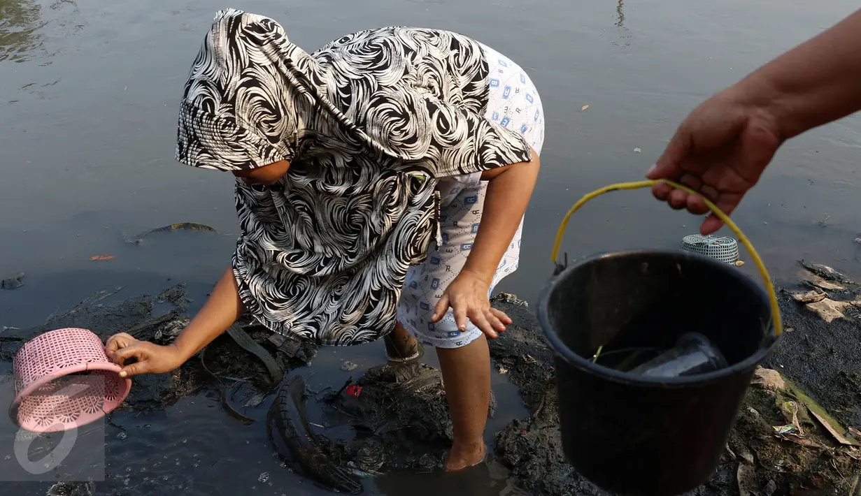 Seorang ibu bersama anaknya mencari ikan dan udang di bantaran Kanal Banjir Timur, Cipinang Muara, Jakarta, Selasa (16/5). Kegiatan itu dilakukan sejumlah ibu bersama anak-anaknya untuk mengisi masa libur sekolah. (Liputan6.com/Immanuel Antonius)