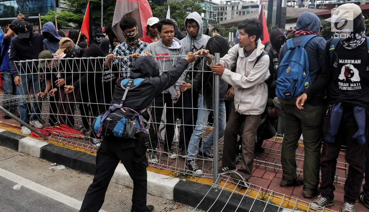 Peserta aksi dari berbagai serikat buruh berusaha merobohkan pagar besi di pelican crossing Tosari saat peringatan Hari Buruh 2019 di Jalan Jenderal Sudirman dekat Bundaran HI, Jakarta, Rabu (1/5/2019). Pagar roboh terdorong massa May Day yang merangsek barikade polisi. (Liputan6.com/Johan Tallo)