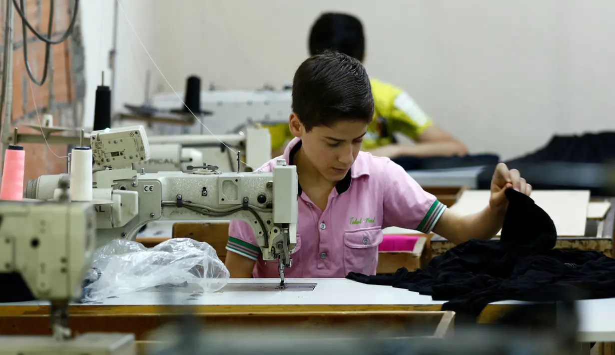 Bocah pengungsi Suriah bernama Muhamed saat menjahit kain di sebuah pabrik tekstil, Istanbul, Turki, (24/6). Meski seumurannya masih menikmati bangku sekolah, mereka menikmati pekerjaan mereka. (REUTERS/Murad Sezer)