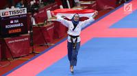 Atlet Taekwondo putri Indonesia, Defia Rosmaniar mengibarkan bendera Merah Putih saat merayakan kemenangan atas Salahshouri Marjan (Iran) pada Final Women Individual Poomsae di JCC, Jakarta, Minggu (19/8). (Liputan6.com/Helmi Fithriansyah)