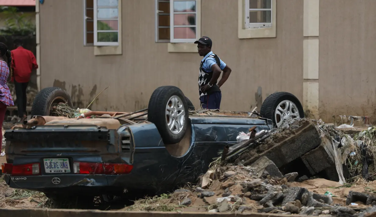 Seorang pria melihat setelah hujan lebat di Trademoore Estate, Lugbe, Abuja, Nigeria (13/9/2021). Badan Manajemen Darurat Nasional Nigeria (NEMA) mengkonfirmasi 3 orang tewas, dan puluhan mobil dan rumah terkena dampak di malapetaka. (AFP/Kola Sulaimon)