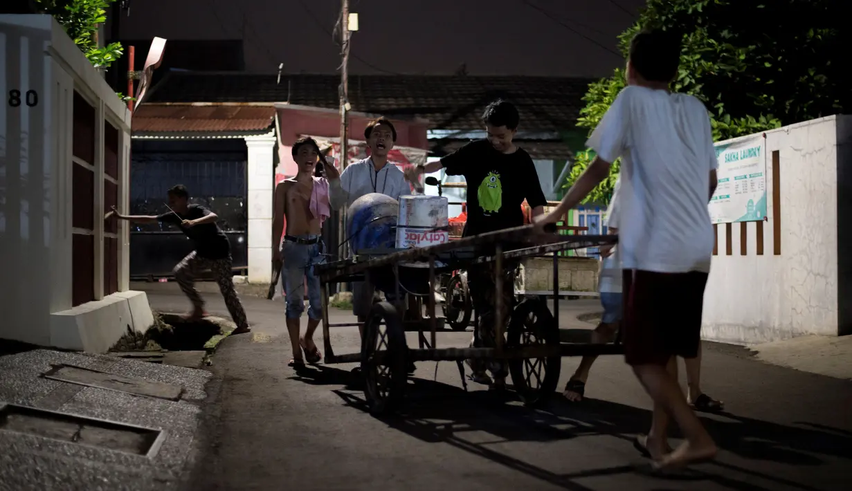 Sejumlah pemuda berusaha membangunkan warga untuk melaksanakan sahur sekitar lingkungan mereka di Jakarta, 19 Mei 2018.  Kegiatan yang dilakukan menjelang sahur tersebut menggunakan tong dan tempat cat bekas. (AFP PHOTO/BAY ISMOYO)