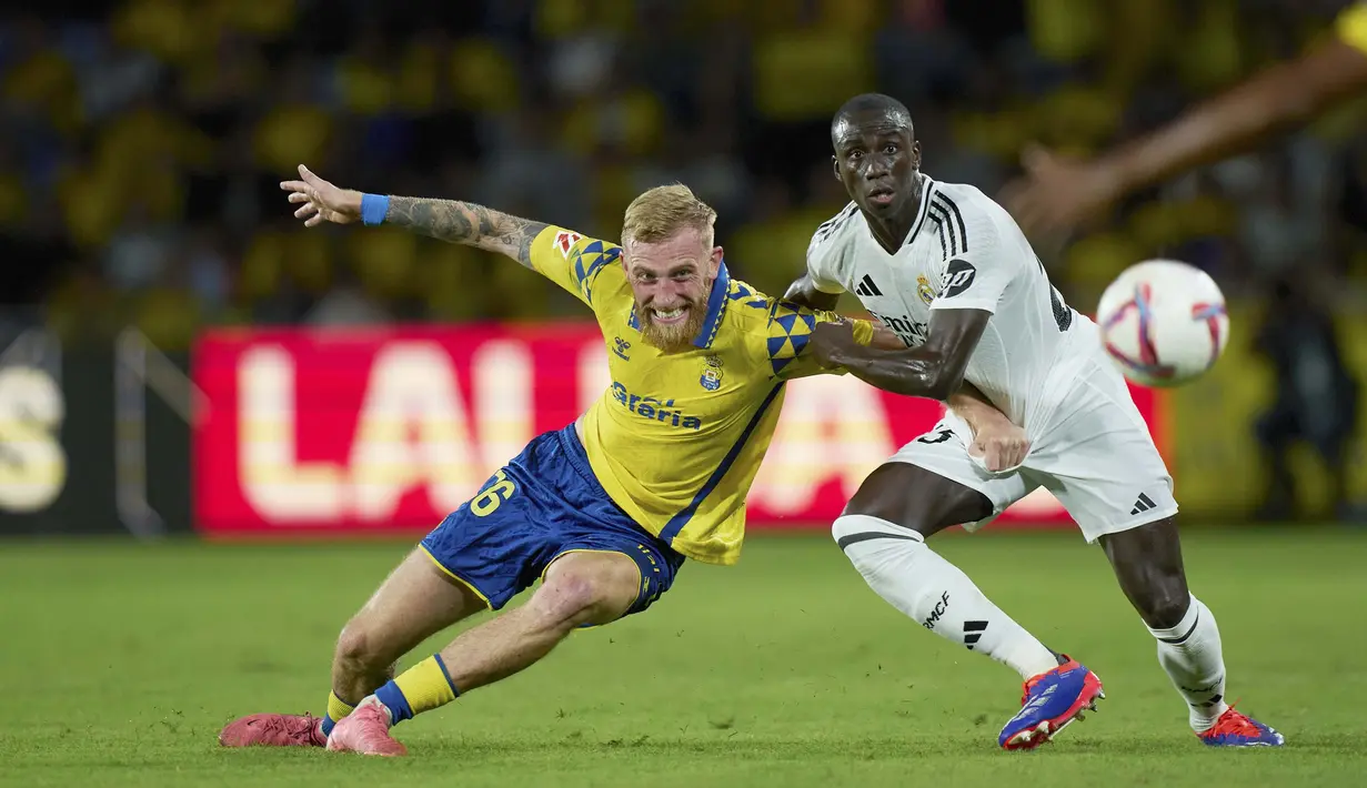 Pemain Real Madrid, Ferland Mendy, berebut bola dengan pemain Las Palmas, Oliver McBurnie, pada laga pekan ketiga La Liga 2024/2025 di Stadion Gran Canaria, Jumat (30/8/2024).  (AP Photo/Gabriel Jimenez)