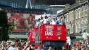 Dari atas bus, para pemain Arsenal melambaikan tangan kepada penggemar fanatik mereka saat parade kemenangan yang dimulai dari depan stadion Emirates, London, Inggris, (18/5/2014). (AFP PHOTO/Oliver Will)