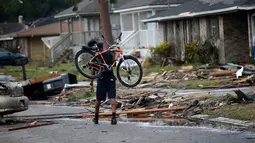 Seorang pria membawa sepedanya berjalan diantara puing-puing rumah yang rusak akibat Tornado di New Orleans, AS (7/2). Selain merusak bangunan dan rumah, sediktnya 25 orang luka-luka akibat hantaman tornado tersebut. (AP Photo/Gerald Herbert)