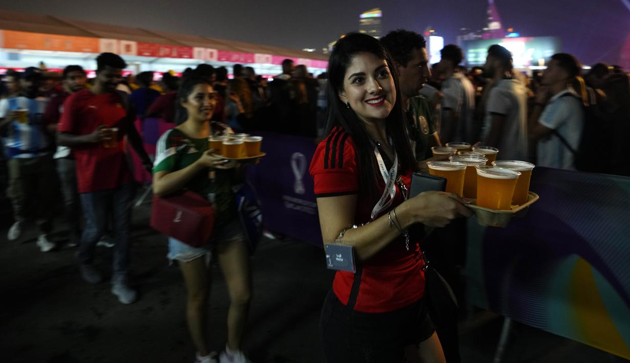 Suporter wanita membawa bir yang disediakan salah satu sponsor saat pembukaan FIFA Fan Festival Piala Dunia 2022 di Al Bidda Park, Doha, Minggu (20/11/2022). (AP Photo/Petr David Josek)