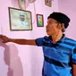 Rusdi, ayah AM, saat menunjukkan foto anaknya yang dipajang di dinding rumahnya, di Kota Palembang Sumsel (Liputan6.com / Nefri Inge)