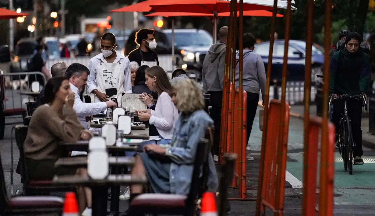 Pengunjung duduk di luar restoran yang menawarkan layanan area luar ruangan (outdoor) di New York pada 3 Oktober 2020. Kota itu mengizinkan restoran membuat area makan outdoor hingga ke trotoar dan jalanan sebagai upaya mengatasi dampak ekonomi COVID-19 yang berkelanjutan. (AP Photo/John Minchillo)