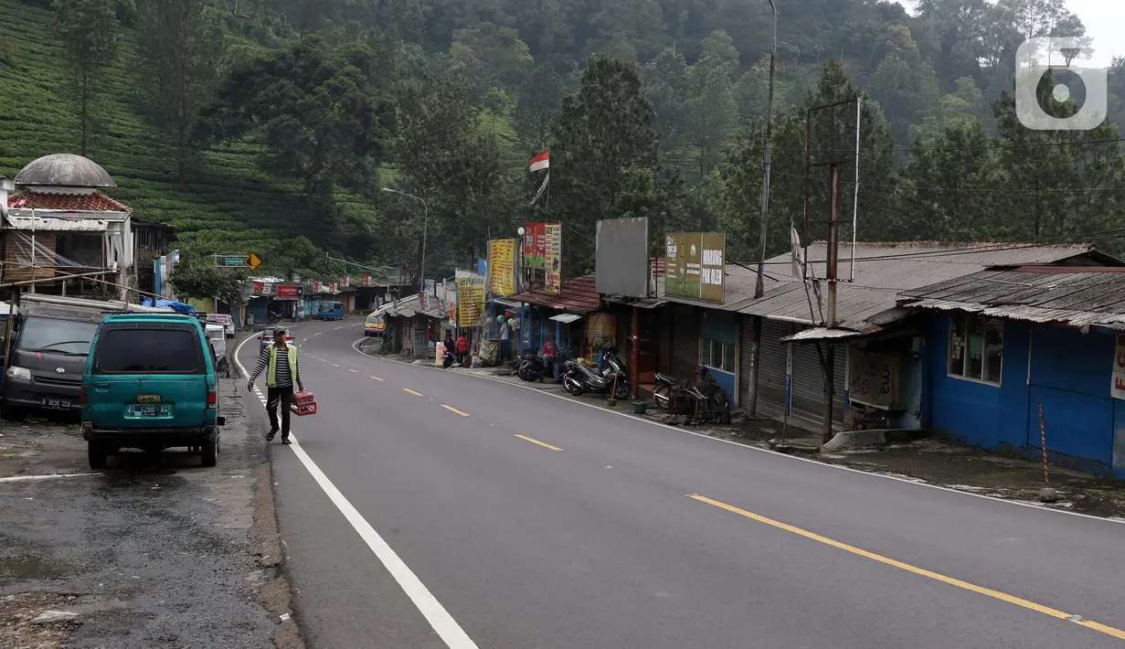 Pejalan kaki melintasi Jalan Raya Puncak, Kabupaten Bogor, Jawa Barat, Minggu (19/4/2020). Arus lalu lintas di kawasan Puncak lengang seiring penetapan status Pembatasan Sosial Skala Besar untuk Kabupaten dan Kota Bogor pada Rabu (15/4) lalu. (Liputan6.com/Helmi Fithriansyah)