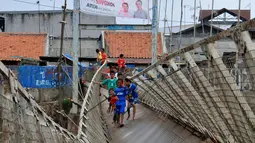 Sejumlah anak-anak melintas di Jembatan Gantung yang rusak di Petamburan, Jakarta Barat, Sabtu (14/06) (Liputan6.com/Andrian M Tunay)