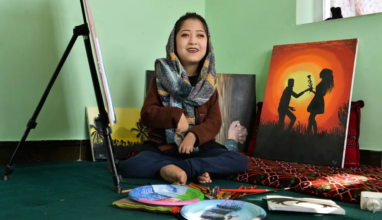 Seniman Robaba Mohammadi duduk di sebelah lukisannya selama wawancara dengan AFP mulut di studionya di Kabul pada 5 Desember 2019. Melalui lukisan, seniman asal Afghanistan ini mengekspresikan bahwa wanita dan disabilitas bukan lagi hal yang bisa dipandang sebelah mata. (NOORULLAH SHIRZADA/AFP)
