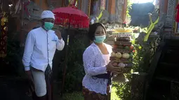 Umat Hindu membawa sesajen saat Hari Raya Galungan di sebuah pura di Bali, Rabu (14/4/2021). Perayaan Hari Raya Galungan yang merupakan hari kemenangan kebenaran (Dharma) atas kejahatan (Adharma) itu diikuti umat Hindu di Bali dengan menerapkan protokol kesehatan. (AP/Firdia Lisnawati)