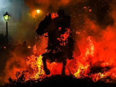 Seorang pria menunggang kuda melintasi kobaran api dalam tradisi tahunan Luminarias memperingati Hari Santo Anthony (santo pelindung hewan) di San Bartolome de Pinares, Spanyol, 16 Januari 2023. Tradisi yang sudah berlangsung selama 500 tahun ini dilakukan sebagai upaya 'pemurnian' hewan dengan cara melintasi kobaran api. (AP Photo/Manu Fernandez)