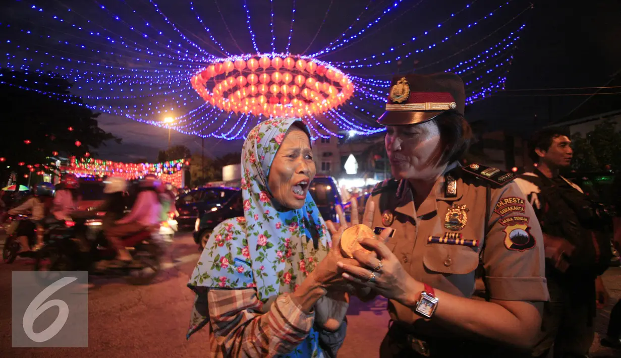 Seorang Polwan membagikan kue keranjang kepada pengguna jalan yang melintas di Pasar Gede, Solo (8/2). Pembagian kue keranjang imlek bertujuan mengkampanyekan anti narkoba dengan slogan, Kue Keranjang Lebih Manis Dari Narkoba. (Liputan6.com/Boy Harjanto)