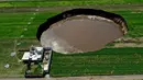 Pemandangan udara dari sinkhole yang ditemukan oleh petani di lahan pertanian di Santa Maria Zacatepec, negara bagian Puebla, Meksiko, Senin (1/6/2021). Warga tiap hari khawatir karena sinkhole terus membesar dan mengancam menelan rumah mereka. (JOSE CASTAÑARES/AFP)