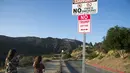 Seorang wanita berjalan di dekat rambu "No Trump Anytime" yang dipasang di jalan utama dekat Bukit Hollywood, California, Rabu (27/4). Rambu anti-Donald Trump itu dibuat seniman jalanan yang memiliki nama sebutan 'Plastic Jesus'. (Robyn BECK/AFP)