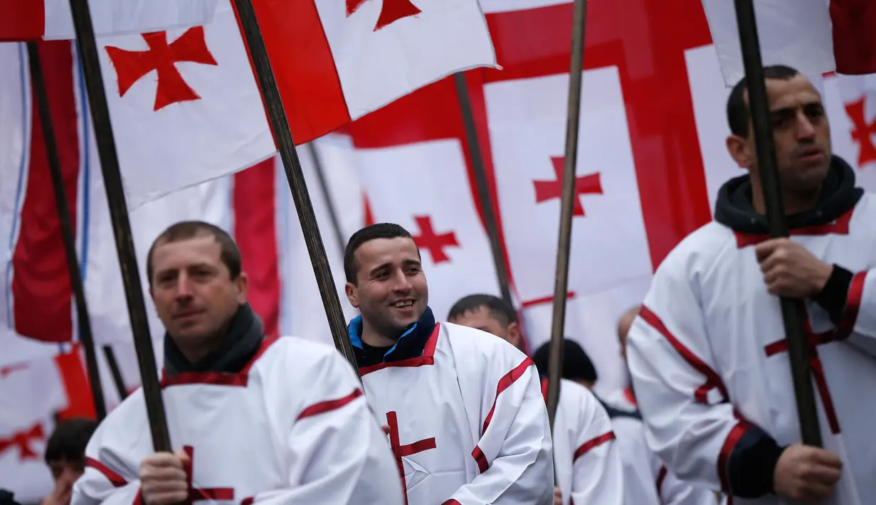 Peserta "Alilo" memegang bendera selama mengikuti pawai bersama di jalanan Tbilisi, Georgia, Kamis (7/1). Para peserta ini merupakan penganut Kristen Ortodoks di Georgia. (REUTERS/David Mdzinarishvili)