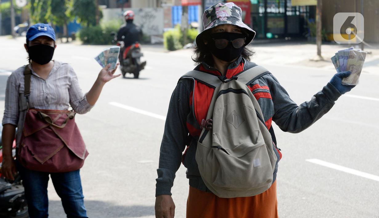 Penjual jasa penukaran uang menawarkan uang baru berbagai pecahan kepada pengguna jalan di kawasan Bintaro Sektor 2, Jakarta Selatan, Selasa (12/05/2020). Pembeli uang kertas baru yang biasanya ramai menjelang Lebaran, kini sepi di tengah pandemi virus corona Covid-19. (merdeka.com/Dwi Narwoko)