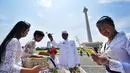 Pemuka agama mencipratkan air suci pada umat Hindu yang akan mengikuti upacara Tawur Agung Kesanga di Silang Monas, Jakarta, Jumat (20/3). Upacara tersebut untuk membersihkan jagat raya sebelum pelaksanaan Nyepi esok harinya.  (Liputan6.com/Faizal Fanani)