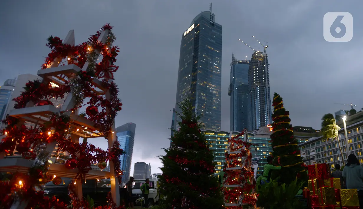 Petugas menghias pohon Natal di Bundaran HI, Jakarta, Kamis (23/12/2021). Christmas Carol dilakukan di tujuh titik yang pada hari ini memasang pohon Natal di beberapa titik tersebut. (merdeka.com/Imam Buhori)