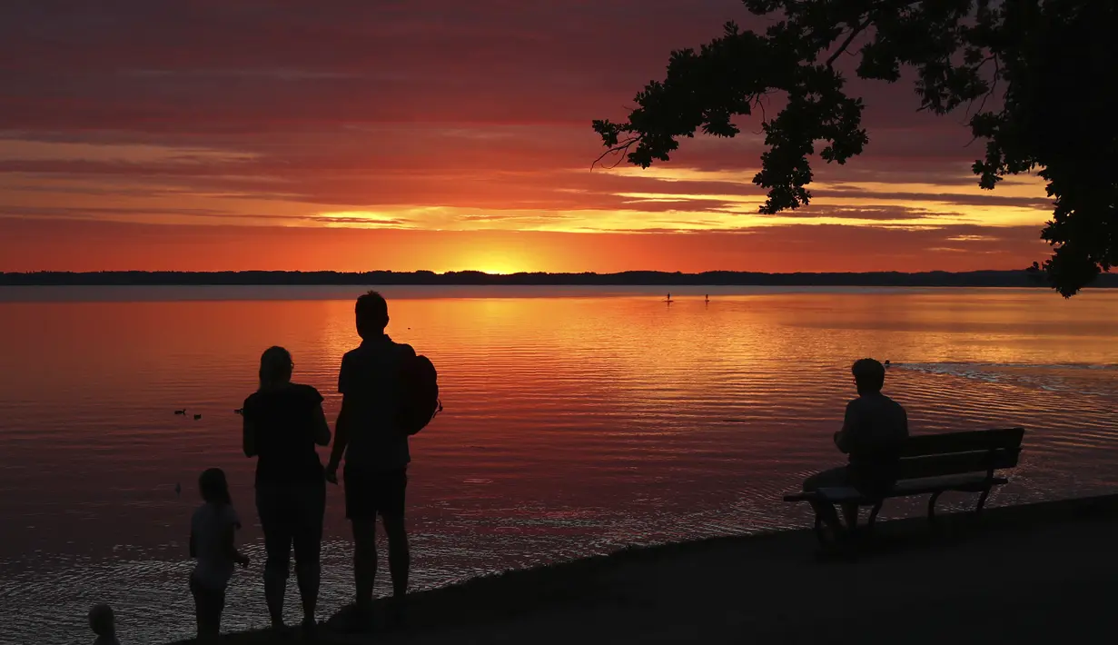 Orang-orang menikmati matahari terbenam di danau Chiemsee di Chieming, Jerman, Selasa, (25/8/2020).  Danau yang terletak di dekat kota Rosenheim ini sering diberi julukan "Laut Bayern'. (AP Photo / Matthias Schrader)