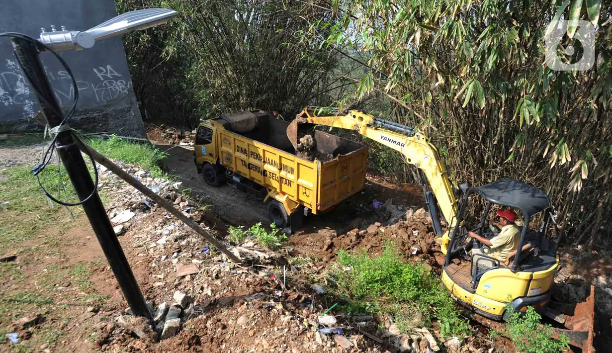 Petugas menggunakan alat berat backhoe membersihan jalan dari longsoran tanah di RT 04/RW 03, Kademangan, Keranggan, Setu, Tangerang Selatan, Banten, Selasa (3/12/2019). Longsor pada Senin sore kemarin menewaskan seorang pengendara sepeda motor yang melintas, Anggi (23). (merdeka.com/Arie Basuki)