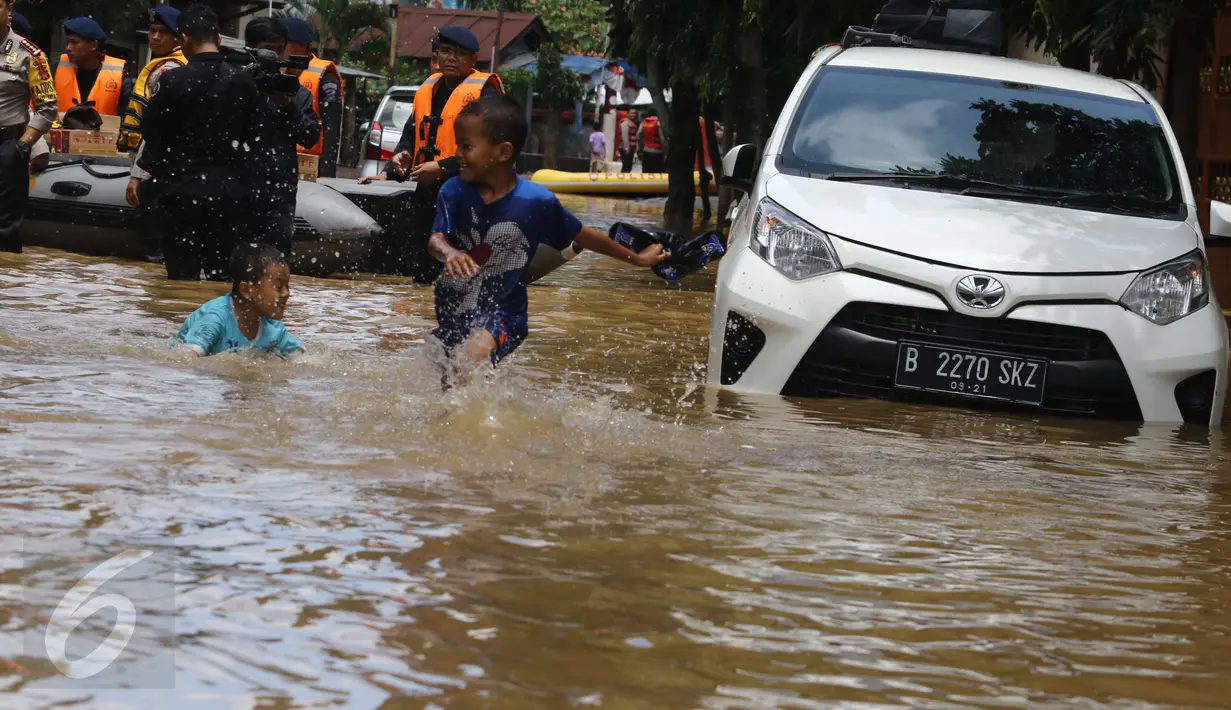 Dua orang anak bermain dekat mobil yang terendam banjir di permukiman Bukit Duri, Jakarta, Kamis (16/2). Meluapnya Bendungan Katulampa, Bogor, menyebabkan kawasan Bukit Duri tergenang air dengan ketinggian 10 - 80 cm. (Liputan6.com/Helmi Afandi)