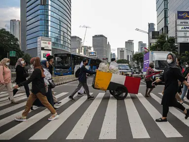 Pekerja kantoran melintas di pelican cross kawasan Jalan Thamrin, Jakarta, Kamis (5/1/2023). Pencabutan Pemberlakuan Pembatasan Kegiatan Masyarakat (PPKM) dinilai untuk menggenjot ekonomi Indonesia 2023 yang diproyeksi suram akibat resesi global. (Liputan6.com/Faizal Fanani)