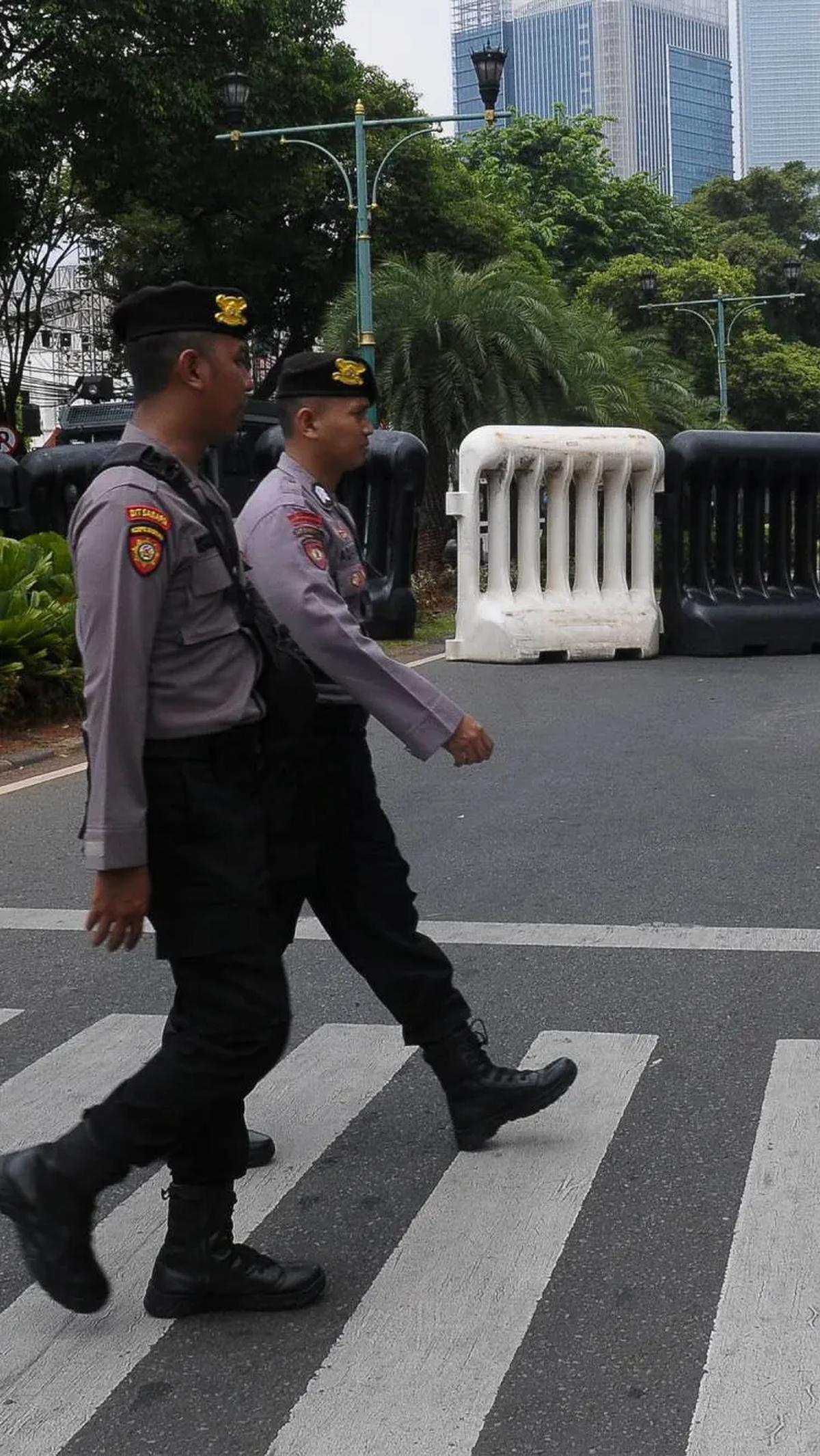 Polisi  melakukan penjagaan saat mengawal pemasangan kawat berduri bareil jelang pengundian nomor urut pasangan calon presiden dan wakil presiden pada hari Selasa (14/11/2023) di KPU.<br>
