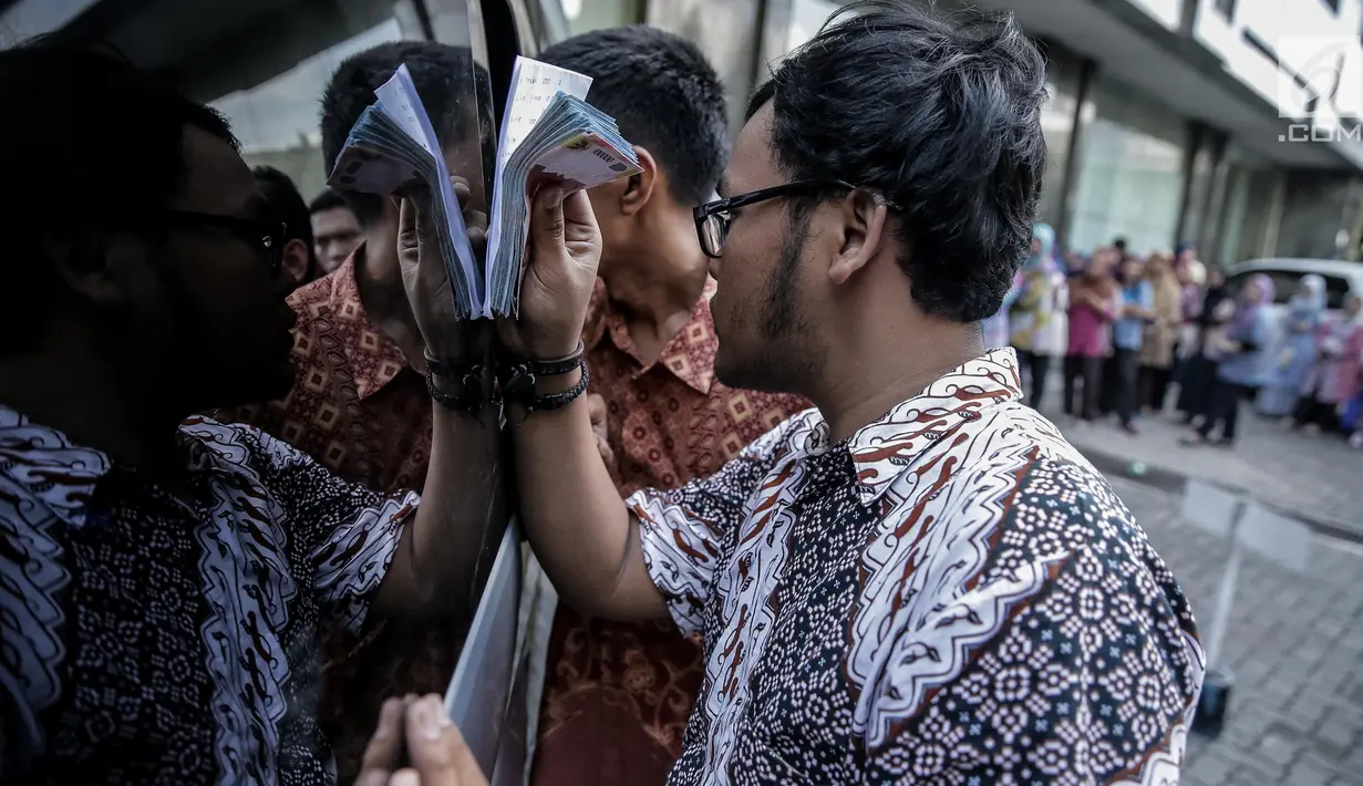 Karyawan melakukan transaksi penukaran uang pecahan ribuan dan puluhan ribu di halaman kantor KKP, Jakarta, Jumat (16/6). Bank Indonesia (BI) menyiapkan pecahan uang untuk kebutuhan Idul Fitri tahun ini sebesar Rp200 triliun. (Liputan6.com/Faizal Fanani)